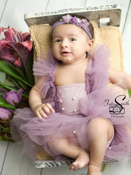 This little princess is surrounded by beautiful purple and white flowers. The overhead shot provides a lovely, artistic perspective on this floral-themed newborn session.