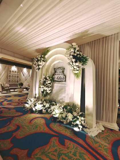 This arched photo backdrop, adorned with white florals, provides a beautiful, dedicated space for guests to capture memories of the celebration.