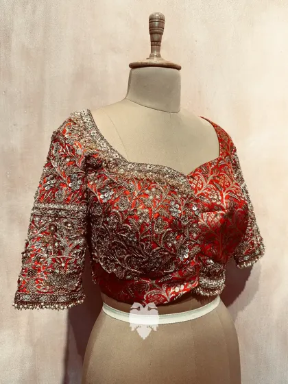 The front of Bhavana's red silk brocade blouse, showing the blend of classic fabric with contemporary embellishments.
