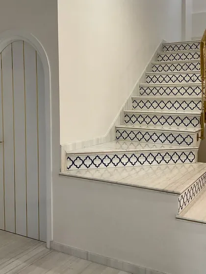 This staircase at the Jolly Residence features intricate patterned tiles on the risers and a sleek brass railing. This detail transforms the staircase into a decorative element that reflects a modern Moroccan-inspired theme.