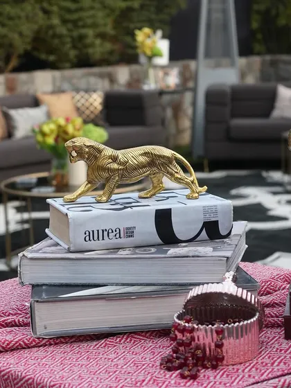 A stack of coffee table books is topped with a golden tiger figurine, creating a stylish and personal decor accent.