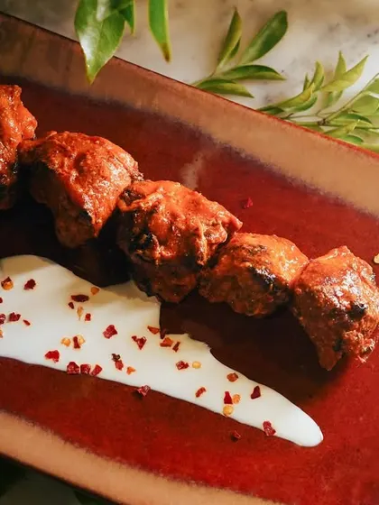 A top-down view of the Chicken Banjara Tikka, showing the sprinkle of chili flakes on the sauce. It's these small details that elevate a simple dish into a gourmet experience.
