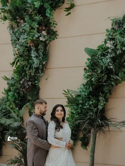 A classic portrait of Gaurav and Mansi posing against a beautiful green foliage wall.