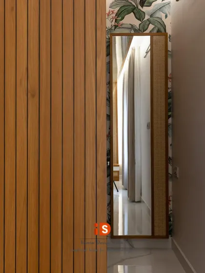 A detail shot showing the use of vertical wood slats and a full-length mirror with a cane-detailed frame, adding texture and depth to the bedroom corridor.