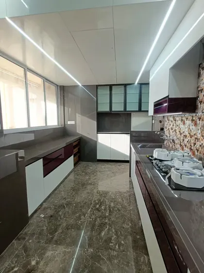 A spacious parallel kitchen combining white and deep purple acrylic cabinets. The mosaic tile backsplash adds texture and color, while the glossy finish on the cabinets enhances the light in the room.