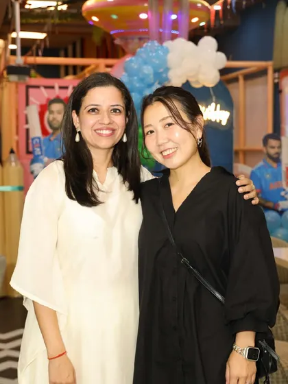 Two guests smiling for the camera during a cricket-themed party.