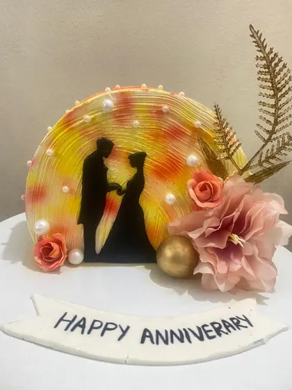 A romantic anniversary cake with a silhouette of a couple against a warm, glowing background.