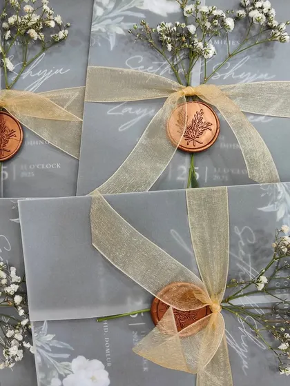 A full display of the vellum-wrapped invitations, each adorned with baby's breath, creating a romantic and ethereal aesthetic.