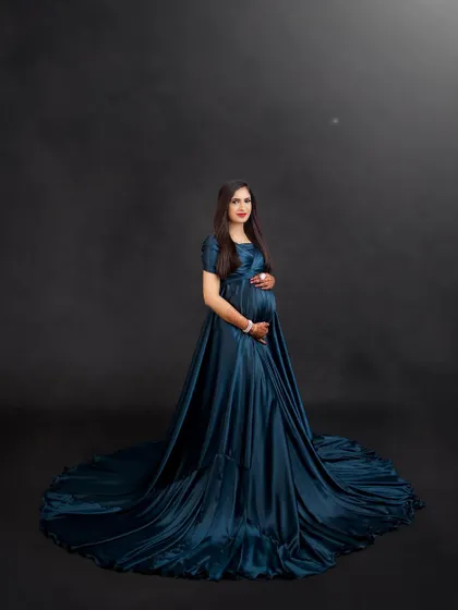 This full-length shot shows how a simple, elegant satin gown can make a powerful statement. The deep teal color is rich and luxurious against the dark backdrop.