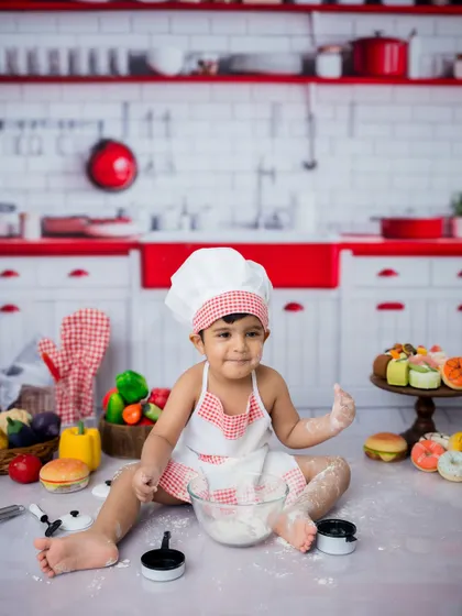 A cheeky grin from our little chef. The red and white kitchen backdrop makes these portraits pop.