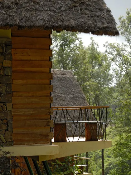 A detail of a cottage balcony at Gorukana. The use of natural wood and rustic metalwork for the railing adds to the eco-resort's aesthetic, which is inspired by the surrounding nature.