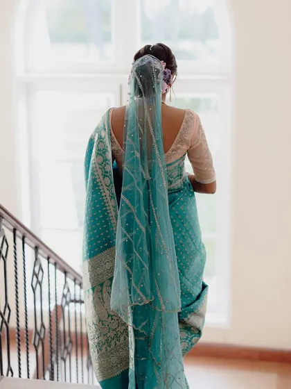 A beautiful shot of the bride from behind, showing the delicate veil and the back of her traditional saree.