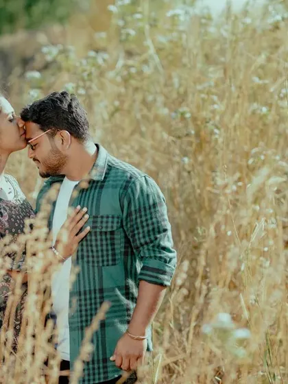 A tender forehead kiss in a field of golden grass. The warm, soft light and natural setting create a deeply romantic and intimate photo.
