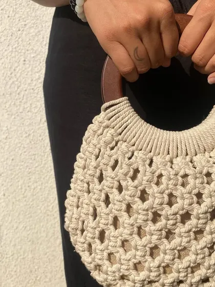 A close-up showing the smooth wooden handle and the tight knotting of the macrame. This bag is perfect for making a subtle statement.