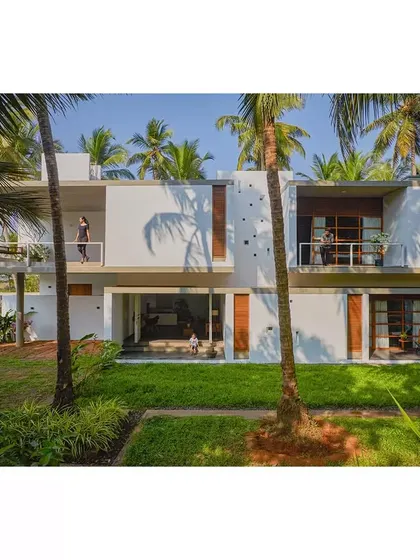 Surrounded by coconut palms, the Aayi House is designed to embrace its tropical setting. The upper-level living spaces open onto deep balconies and terraces, blurring the boundary between the home and the lush garden.