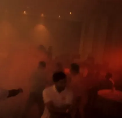 The dance floor is shrouded in red smoke and light at this intense corporate party.