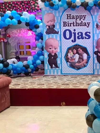 The main stage for the Boss Baby party, featuring a large backdrop with the birthday boy's name and photo, surrounded by character cutouts and balloon decorations.