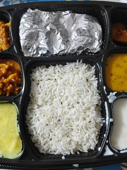 Here’s an inside look at one of my premium thalis. You can see the different compartments holding rice, dal, sabzi, kheer, and raita, with rotis wrapped in foil to keep them warm and soft.