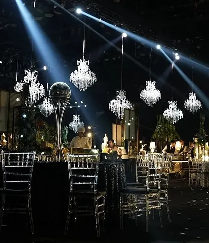 A sangeet setup where classic crystal chandeliers meet modern spotlights, creating a dramatic and glamorous atmosphere.