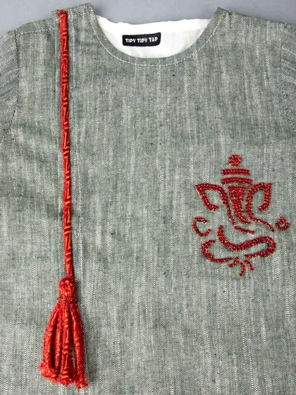 A close-up of the red Ganesha embroidery and tassel on a grey kids' kurta.