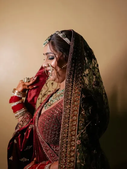 A close-up of a bride in a rich velvet maroon lehenga. This shot highlights the detailed embroidery on the blouse and the heavy dupatta, a signature of our premium bridal rental range.