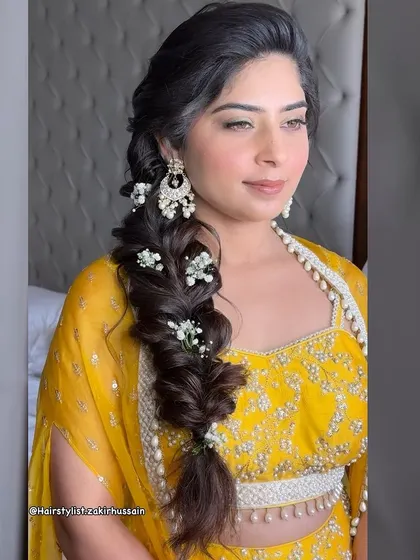 A beautiful side-swept fishtail braid adorned with baby's breath. This is a classic and romantic hairstyle that works well for a variety of wedding events, from the engagement to the reception.
