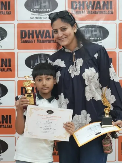 A proud mother with her son, who holds his certificate and two trophies. We celebrate the achievements of our students as a family.
