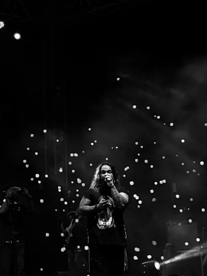 A dramatic black and white shot of our frontman connecting with the audience under the spotlights. This is pure rock and roll.