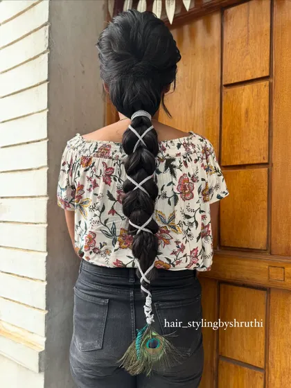 A creative bubble braid wrapped with a white ribbon and finished with a peacock feather. This is an artistic and unconventional style, perfect for a themed event or photoshoot.