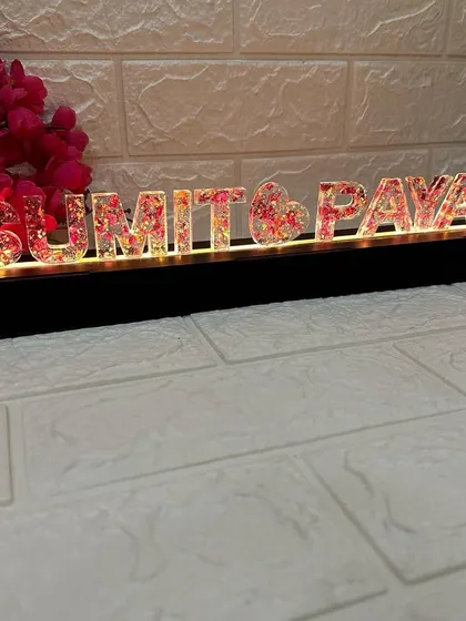 The warm glow of the LED lights illuminates the names from within, creating a beautiful and romantic effect in a dim room.