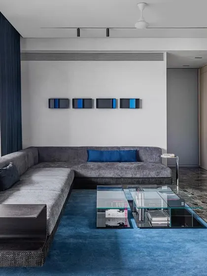 The custom L-shaped sofa in 'A Wedged Haus' includes an integrated side table. This piece was designed to fit the specific dimensions of the living room, demonstrating how furniture can be tailored to the architecture.