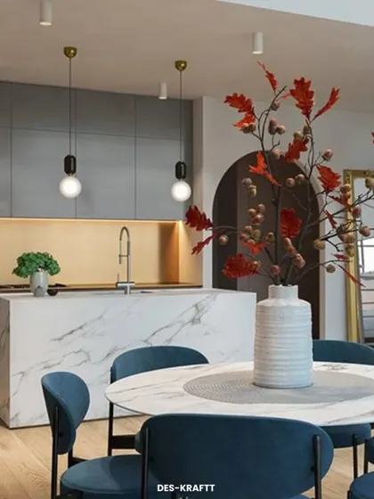 This perspective connects the kitchen island to the dining area, where bold blue chairs provide a splash of color against the neutral and marble backdrop.
