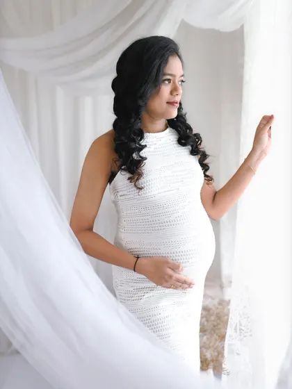 Looking out the window, as if dreaming of the future. This is a classic, contemplative pose that captures the quiet moments of pregnancy.