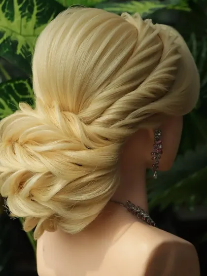A side view of a beautiful reception bun, highlighting the twisted front and textured back. This is a popular choice for modern brides and their families.