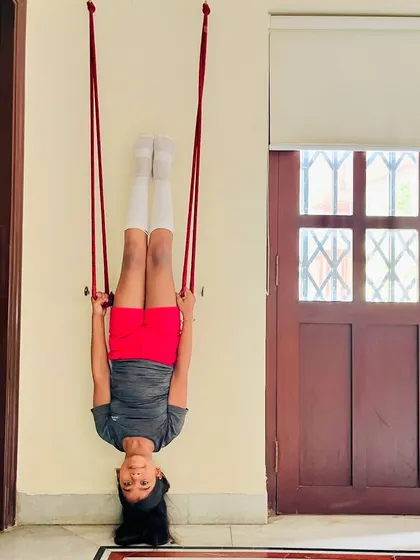 A young student holds an inversion using wall ropes, a technique we use in aerial yoga and gymnastics to build confidence and strength.