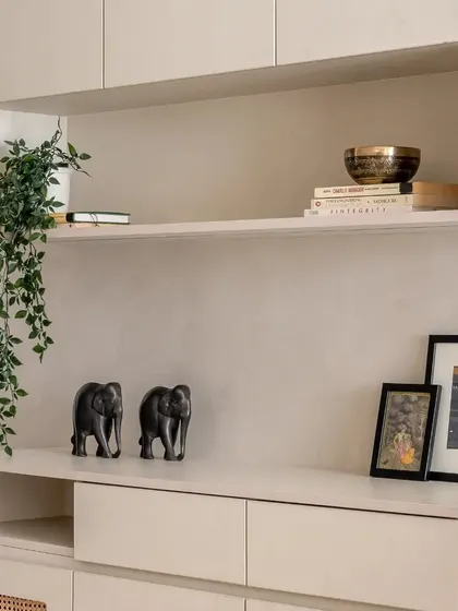 A close-up of the open shelving on the foyer unit, styled with books, a singing bowl, and decorative elephants.