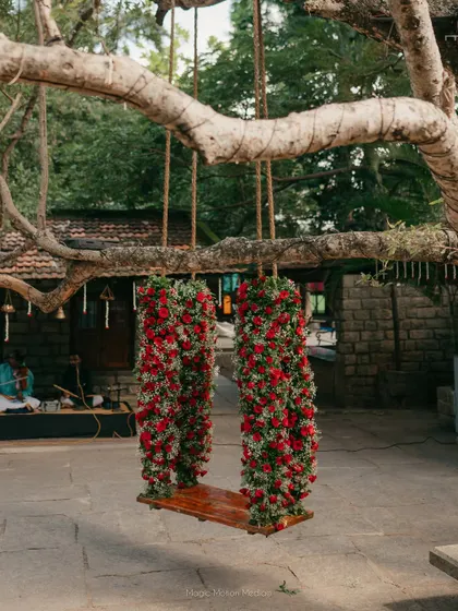 A swing lavishly decorated with deep red roses, perfect for a bold and romantic wedding theme.