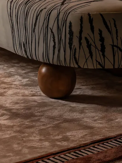 Every detail is considered, right down to the feet of the furniture. Here, the custom-printed fabric of the sculptural armchair meets a solid wood bun foot, resting on a plush, textured rug. This interplay of materials is central to our design approach.