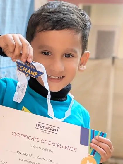 A smile of victory. This young champion proudly displays his 'Champ' medal and certificate, a testament to his effort and enthusiasm during our sports day.