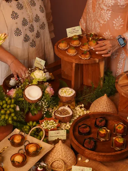 An elaborate festive setup with our team presenting a variety of Indian canapés. The table is decorated with traditional elements like coconuts, jasmine flowers, and marigolds, creating an authentic and welcoming atmosphere for a celebration.