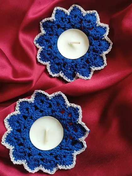 A pair of our royal blue crochet diya coasters with a contrasting silver edge. These holders are perfect for adding a pop of cool color to your warm Diwali lights.