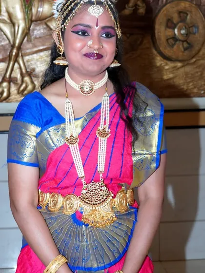 A poised, full-body shot of the dancer, showcasing the elegance of her stance and the rich fabric of her costume.