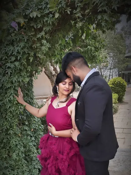 An intimate moment captured in a garden. The client wears our maroon ruffled gown, a romantic choice for a couple's photoshoot.