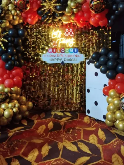 The casino-themed Diwali backdrop set up on a patterned carpet for a house party.