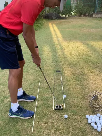A beginner putting lesson setup. Using a putting gate and alignment sticks helps the student visualize the correct path and ensures the putter face stays square at impact.