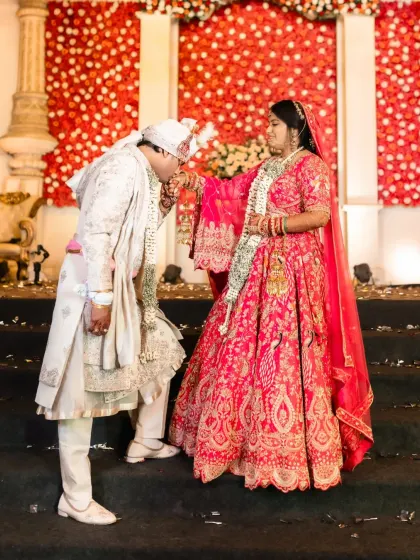A chivalrous moment as the groom kisses the bride's hand on the stage steps.