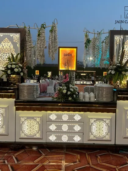 An intricately designed buffet station with illuminated panels and floral decor. This setup is perfect for an elegant evening reception, adding a touch of glamour to the dining experience.
