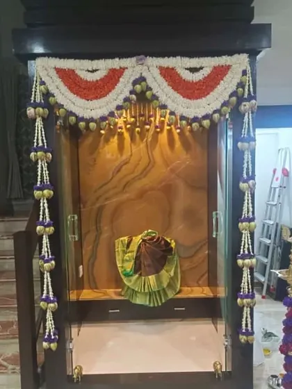 Elegant decor for a pooja unit using garlands of jasmine and other traditional flowers. The hanging elements add a graceful touch to the sacred space.
