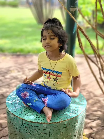 A young student finds her center during an outdoor meditation session. Teaching mindfulness in nature is a beautiful way to help children connect with their inner peace.