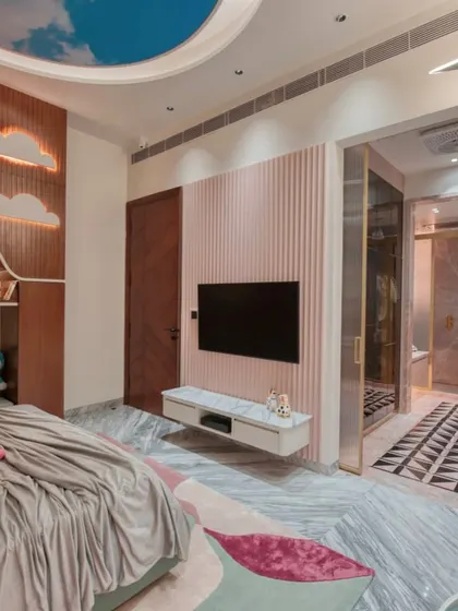 Another view of the kid's bedroom, showing the fluted pink accent wall with a mounted TV and a glimpse into the walk-in closet.